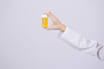 Hand holding a yellow medicine pill bottle