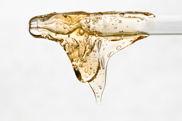Naklejka premium Close-up of a pipette with yellow cosmetic texture flowing down.
