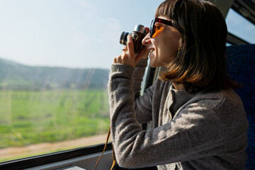 A happy young woman takes photos from a train window. The tourist creates content for social media. The concept of travel and discovery.
