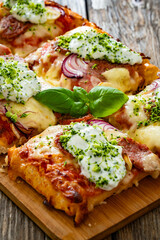 Pizza with sausage, mozzarella cheese, tomato sauce, red onion and broccoli yogurt on wooden table	