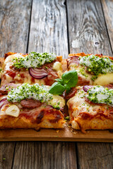 Pizza with sausage, mozzarella cheese, tomato sauce, red onion and broccoli yogurt on wooden table	
