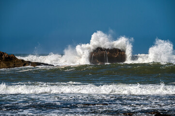 Waves crash powerfully against rocks near Essaouira, highlighting nature's beauty.