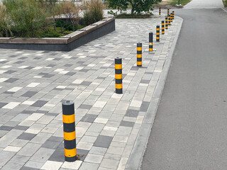 Row of striped bollards on paved urban pathway