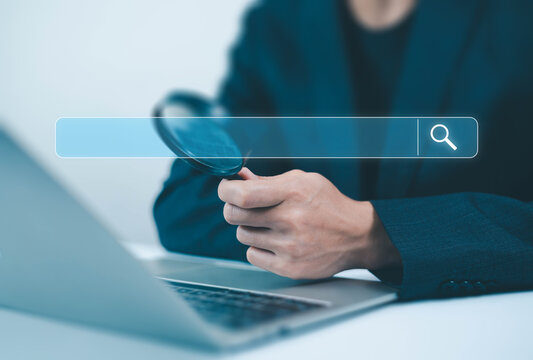 Businessman holding magnifying glass with search bar interface, online search and investigation concept, data research, SEO analysis, information discovery and digital business technology background.