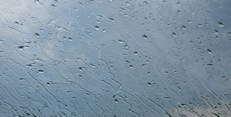 Rain streaks on glass against moody sky. abstract background of bad weather
