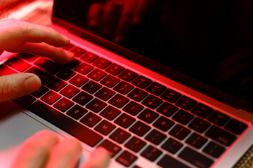 Working on a neon computer keyboard with colored backlighting. Computer video games, hacking, technology, internet concept. Selected focus. 