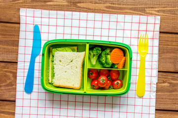 green lunch box for kid on wooden background top view