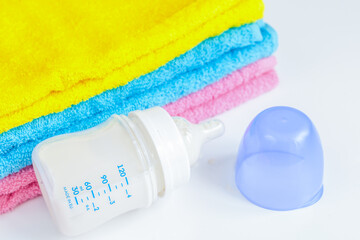 baby bottle with milk and towel on white background