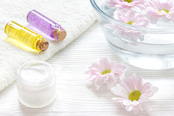 flowers in bowl and oil on wooden background