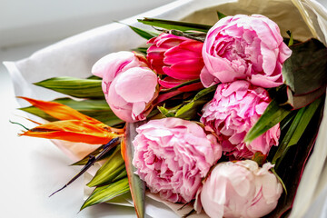 Bouquet of peonies in kraft paper on windowsill