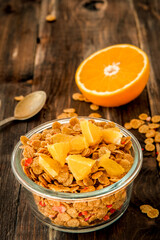 flakes in bowl with orange slices on dark wooden background