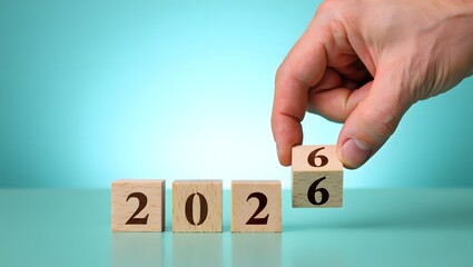 Wooden blocks display changing year from 2026 in hand against backdrop