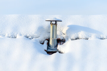 Metal roof vent pipe protruding from deep snow on rooftop in winter