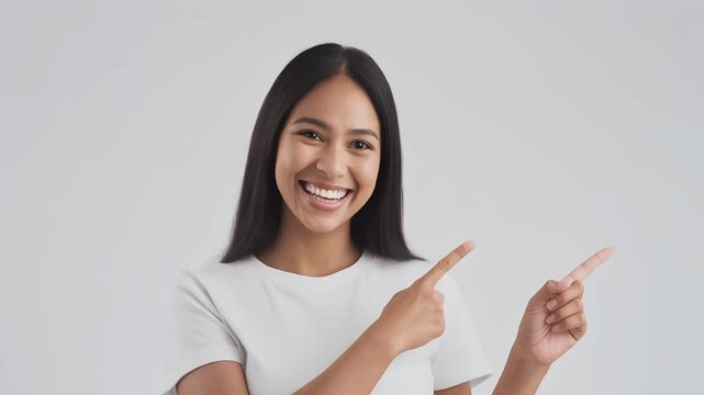 Radiant young woman with a beautiful smile enthusiastically pointing with both hands, showcasing an opportunity or presenting information effectively