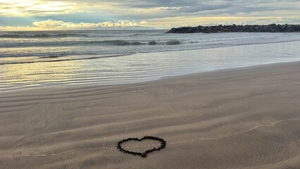 Heart shape drawn in wet sand on empty beach at calm ocean shoreline
