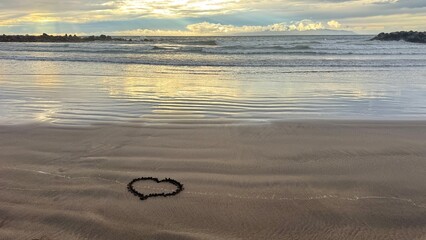 Heart shape drawn in wet sand on empty beach at calm ocean shoreline
