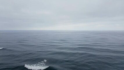 Vast Ocean Under Overcast Sky With Gentle Waves Rolling Underneath a Moody Grey Cloudy Horizon