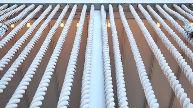 White nautical ropes hanging creating a repeating pattern with warm lights