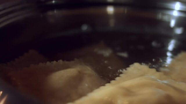 Placing freshly made ravioli in a pan with boiling water, macro view
