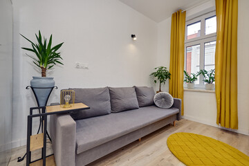 Salon w nowoczesnym apartamencie z szarą sofą i musztardowymi zasłonami © arteffect.pl