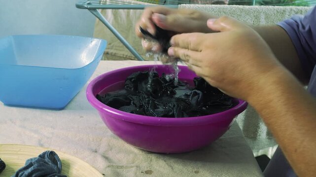 A man washes socks in a basin