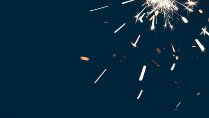 Blurred sparks from sparklers on dark backdrop with copy space for holiday celebration and...