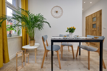 Salon w nowoczesnym apartamencie – jadalnia ze stolikiem z talerzami, duży zielony kwiat w doniczce © arteffect.pl