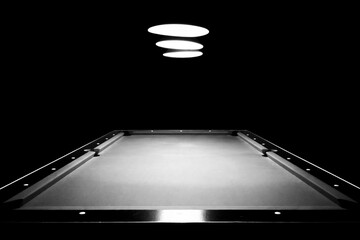 Empty pool table under overhead lights in black and white