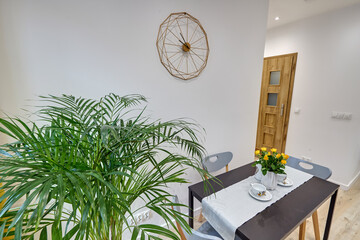 Salon w nowoczesnym apartamencie – jadalnia ze stolikiem z talerzami, duży zielony kwiat w doniczce © arteffect.pl