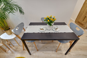 Salon w nowoczesnym apartamencie – jadalnia ze stolikiem z talerzami, duży zielony kwiat w doniczce © arteffect.pl