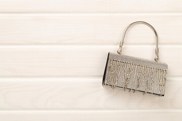 Handbag with beads on wooden background, top view