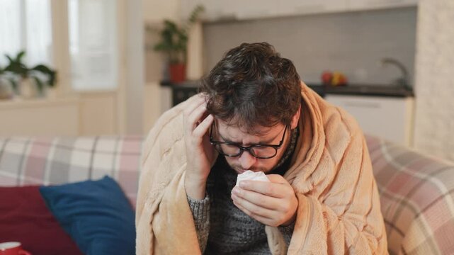 Lament Man in Eyeglasses Experiencing Cold, Flu, Headache, Coughing, and Sneezing under a Duvet