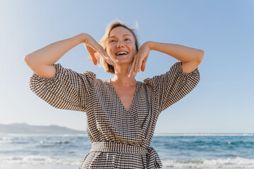 Portrait of happy young woman enjoying fresh air on the beach. Beautiful smiling female having fun...