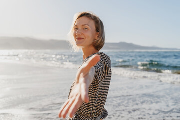 Portrait of happy young woman enjoying fresh air on the beach. Beautiful smiling female having fun on the ocean. Concept freedom and carefree vacation. Beach Holidays.