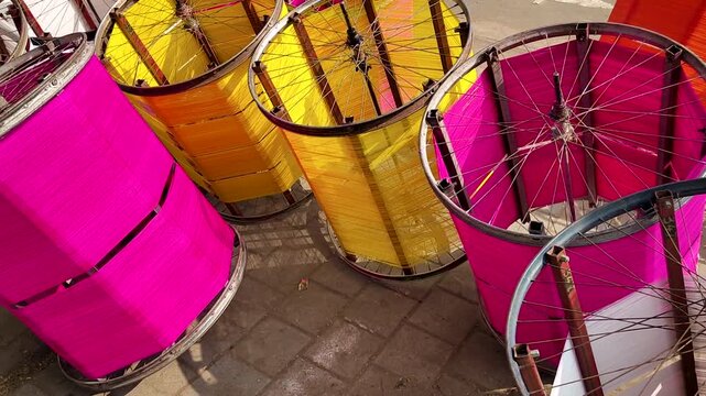 Kite thread spools prepared for kite festival in India, bright cotton strings wrapped on metal frames, traditional celebration preparation, colorful cultural craft background
