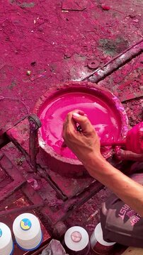 Kite string dye preparation in India showing manual mixing of bright pink color for manja thread vertical view, traditional process used before Makar Sankranti and Uttarayan festival.