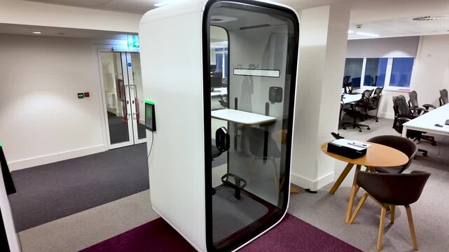 A modern office space features white soundproof phone booths designed for private calls and focused work. These quiet pods offer a solution for open office layouts and collaborative environments.