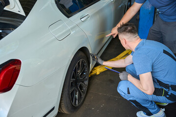 Adult mechanic inspects a car wheel on a lift