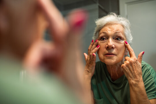 Senior woman examining face in mirror