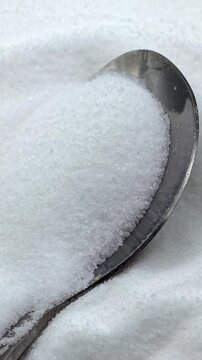 Natural sea salt crystals on a silver spoon for cooking, vertical video