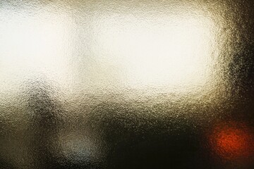 Abstraktes Motiv mit Glasscheibe mit Muster vor Raum mit brauner Fassade und gro&szlig;em wei&szlig;en Licht bei Sonne und Frost am Nachmittag im Winter als Hintergrund