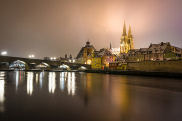 Regensburg mit Domblick auf Dom Sankt Peter und Steinerne Br&uuml;cke nachts im Winter mit Schnee und Beleuchtung, Deutschland