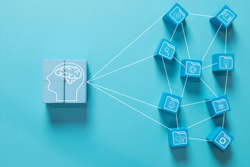 Wooden blocks with brain icon connecting to digital resource folders. Concept of knowledge management, data network, education system, and smart learning organization on blue background.