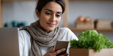 Young hispanic female using smartphone at home with fresh vegetables in kitchen