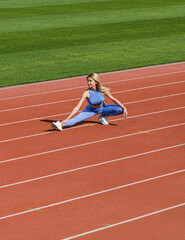 Fototapeta premium Fit girl do outward lunging. Sports exercises and stretching in the stadium. Physical training girl