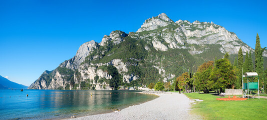 lakeside Gardasee with sunbathing lawn and mountain view. tourist resort Riva del Garda