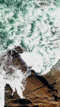 Aerial view hovering above ocean waves and rocky coast, Ancora, Portugal, vertical video