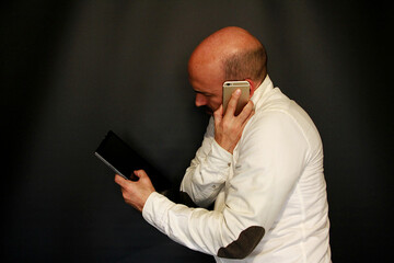 hombre de negocios multitarea con m&oacute;vil y tablet trabajando