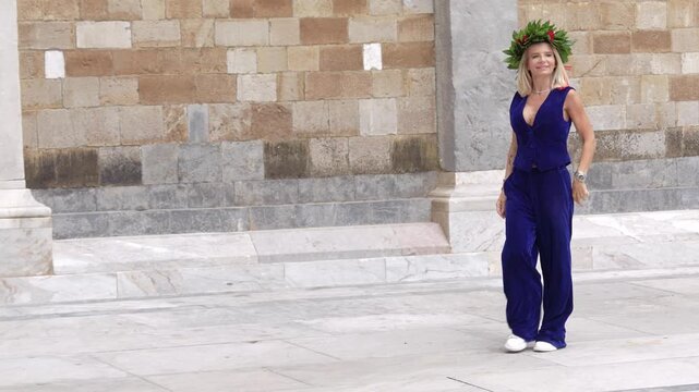 Happy female graduate with diploma and laurel wreath in front of Pisa Cathedral complex at sunset