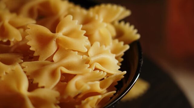 Cooking farfalle pasta in a black bowl with focused close-up of uncooked noodles